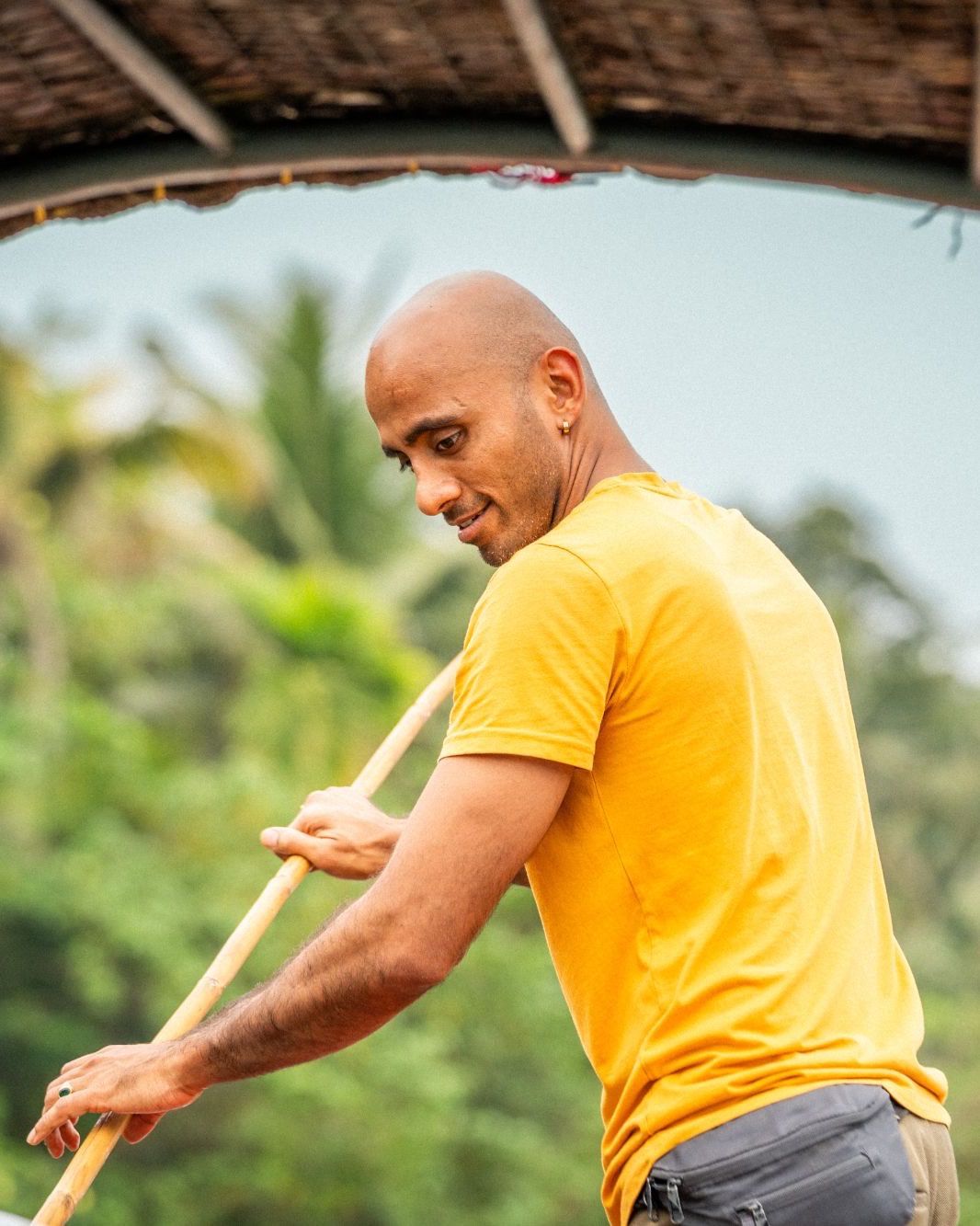 Pratiush Sharma poling a boat through Kerala backwaters, palms behind him